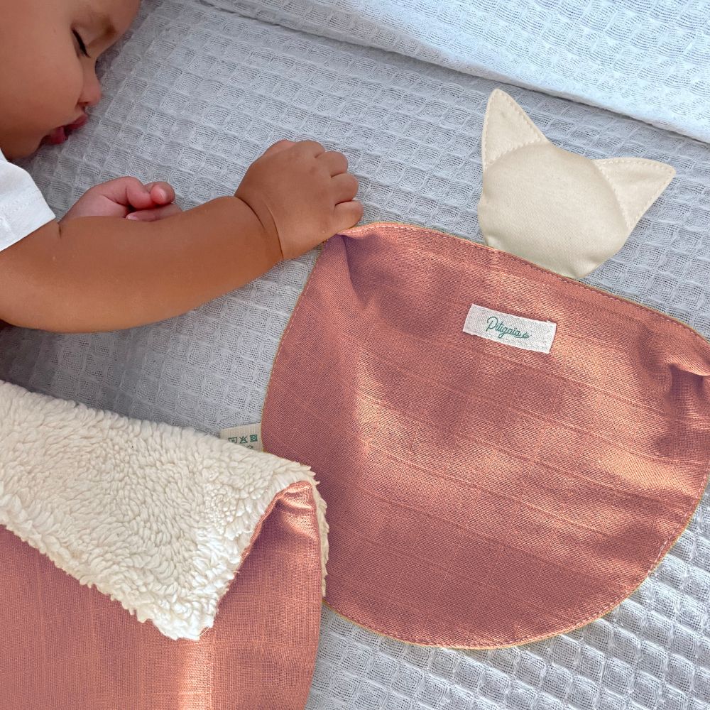 photo d'un bébé qui dort en tenant un doudou plat bio