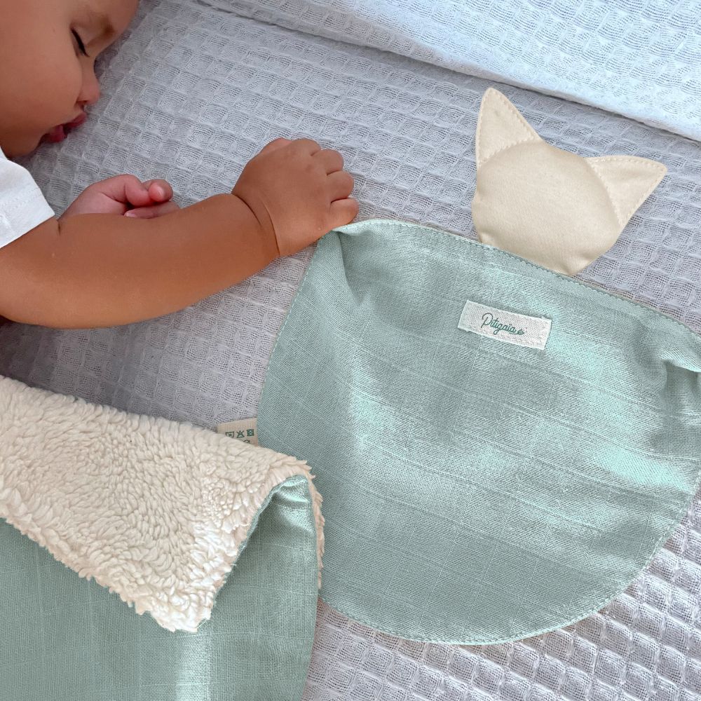 photo d'un bébé qui dort en tenant un doudou plat bio